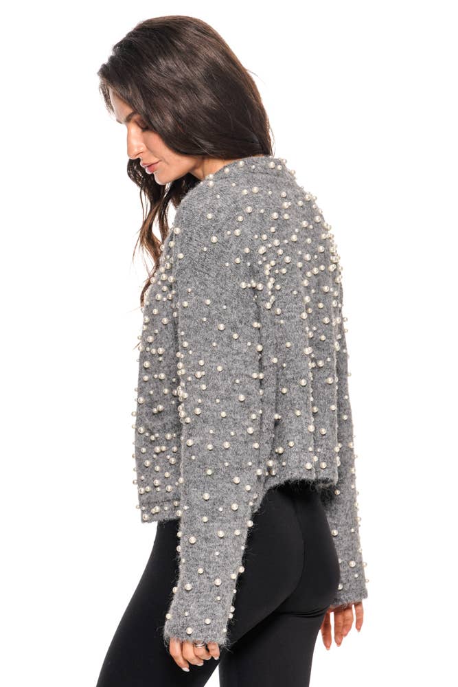 Woman wearing a gray textured sweater with white embellishments on a white background
