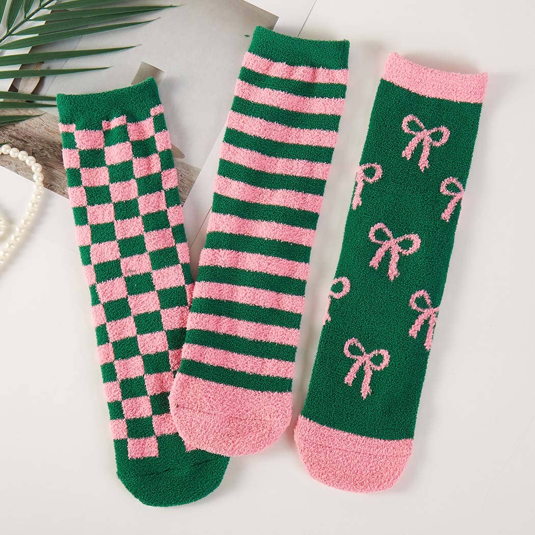 Three pairs of green and pink socks with different patterns on a light background.