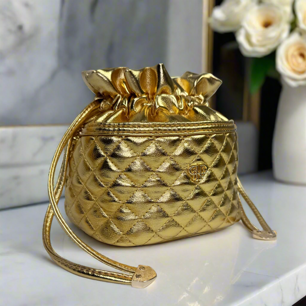 Gold quilted handbag on a white surface with a blurred background