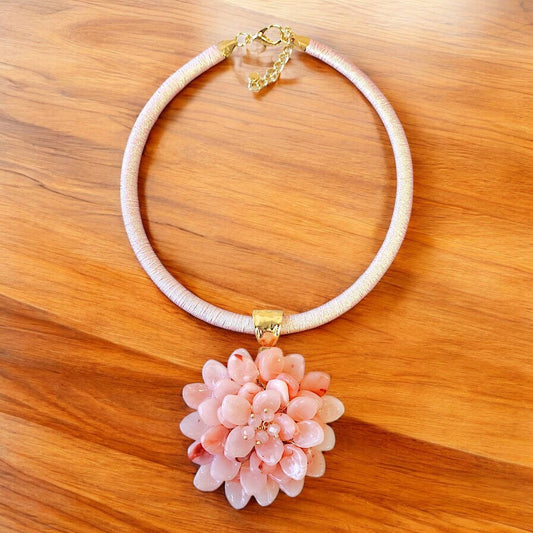 Necklace with a pink floral pendant on a wooden surface