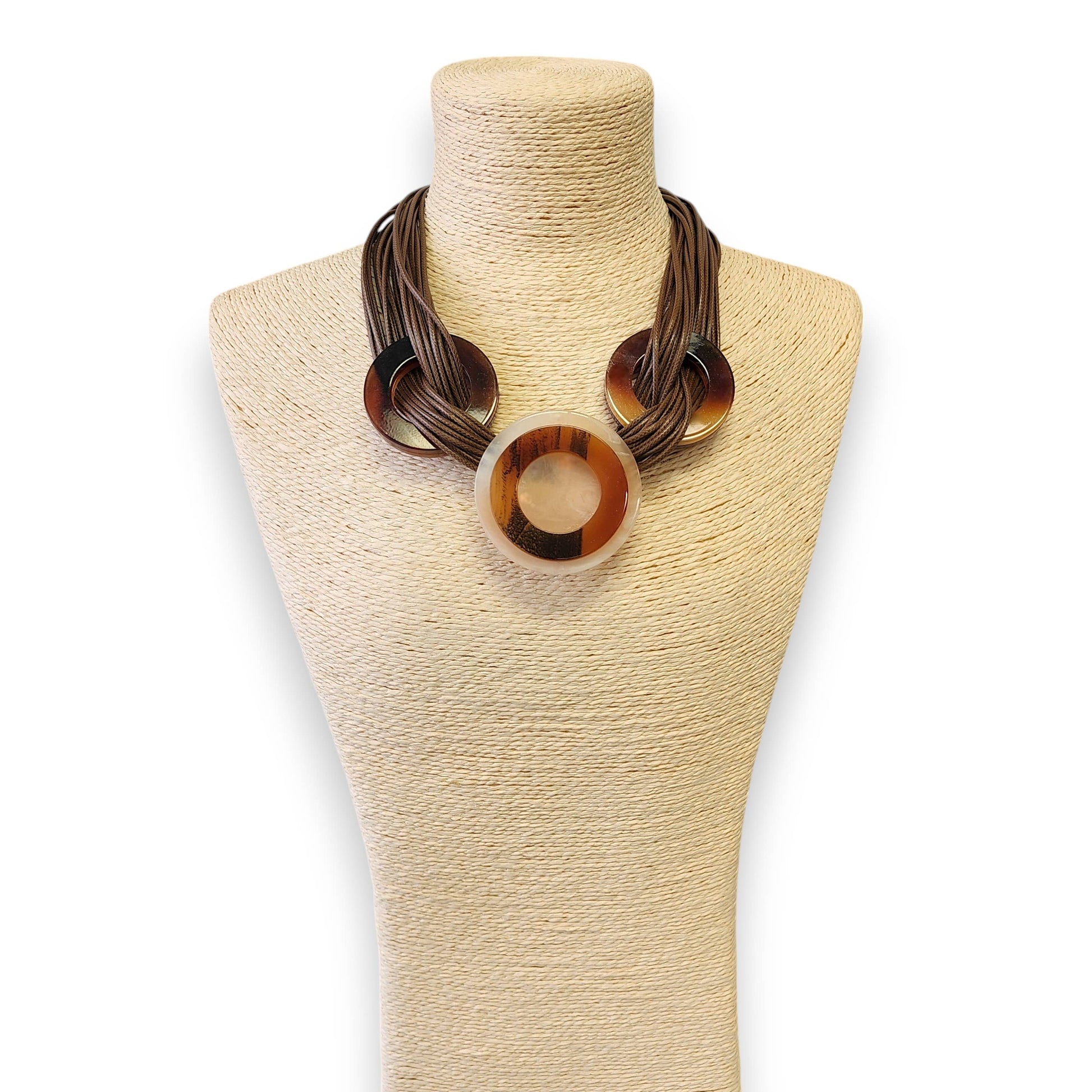 Necklace with tortoiseshell circular pendants on a beige mannequin bust.