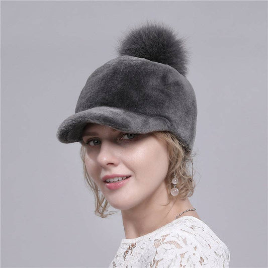 Woman wearing a gray cap with a fur pom-pom on a gray background