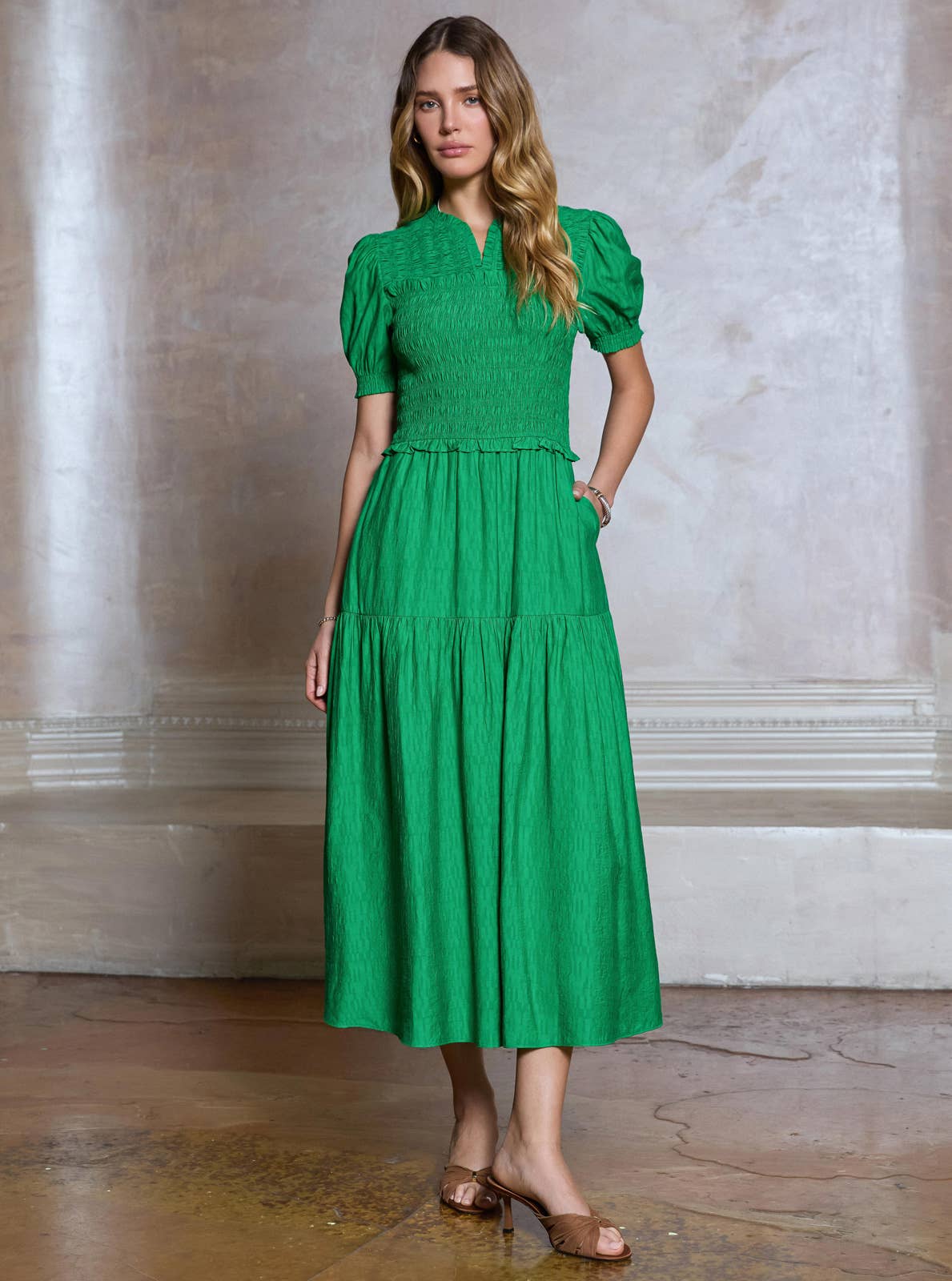 Woman wearing a green dress standing against a classical architecture background
