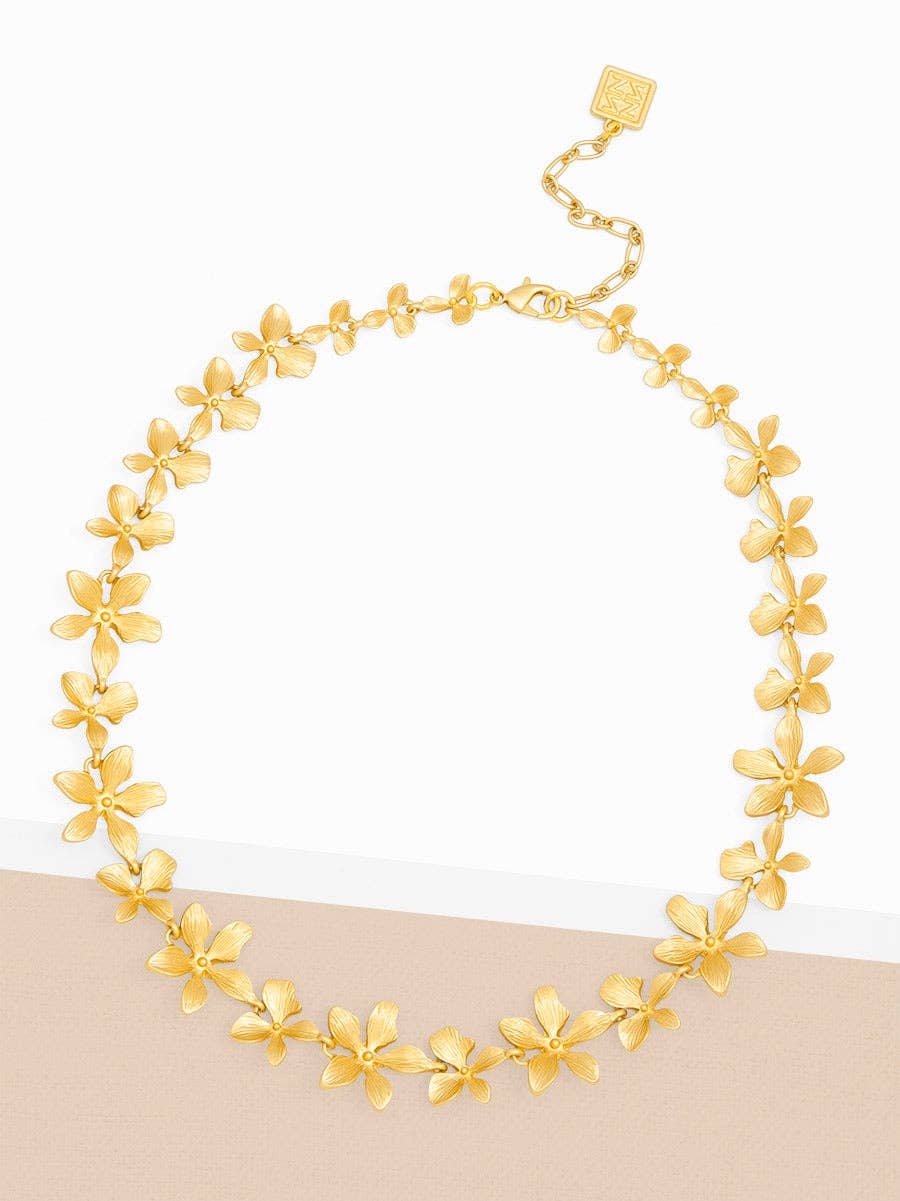 Gold floral necklace on a beige and white background