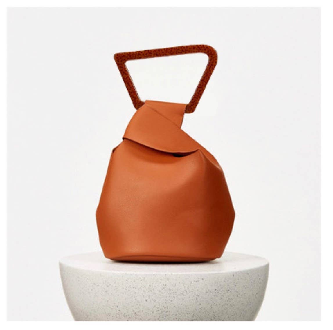 Orange leather bag with a handle on a white background