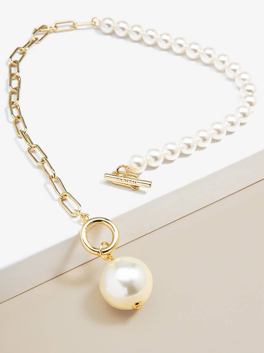Pearl necklace with gold chain and pendant on a light background