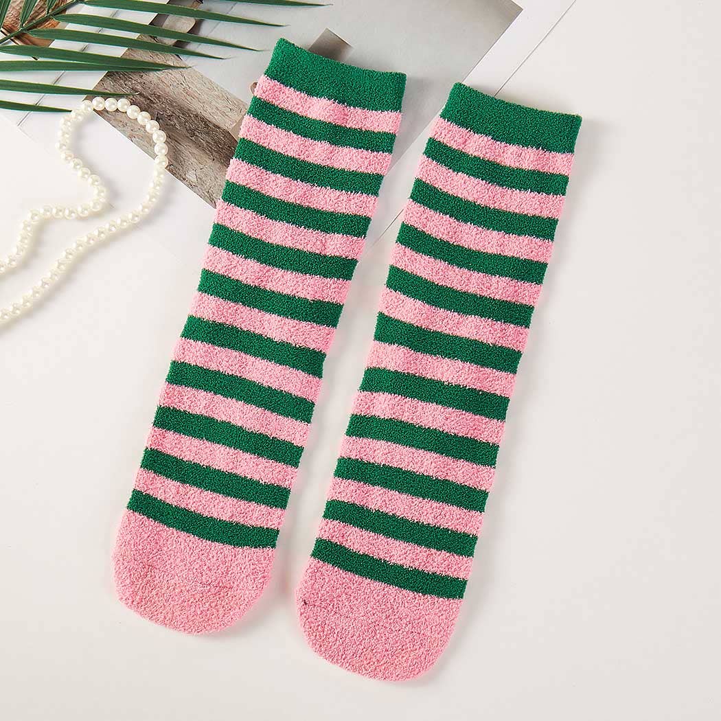 Pink and green striped socks on a light surface with a pearl necklace.