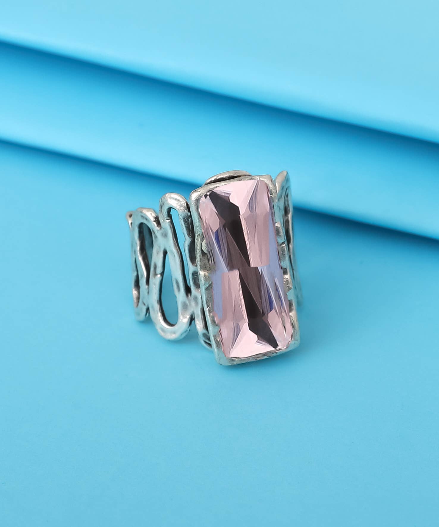 Silver ring with a pink gemstone on a blue background