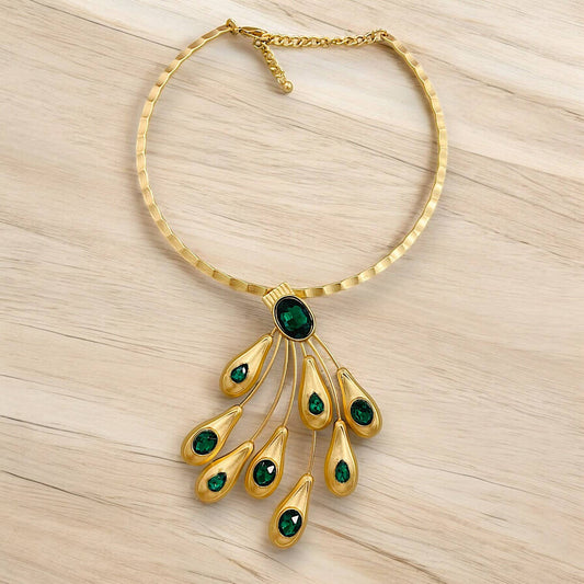 Gold necklace with green gemstones on a light wood background