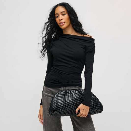 Woman holding a black clutch against a plain background