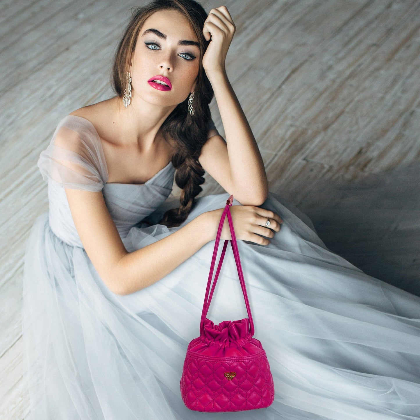 Woman in a light blue dress holding a pink handbag against a neutral background