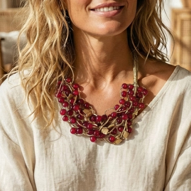 Woman wearing a red beaded necklace with a neutral background