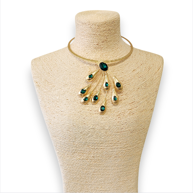 Gold necklace with green stones on a mannequin bust against a white background