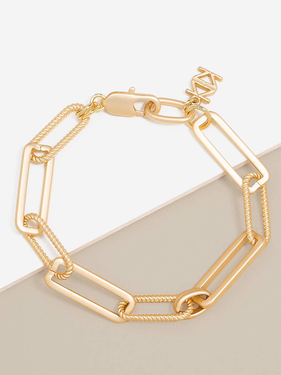 Gold chain bracelet on a light gray surface