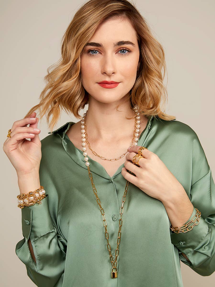 Woman wearing a green blouse with jewelry on a beige background