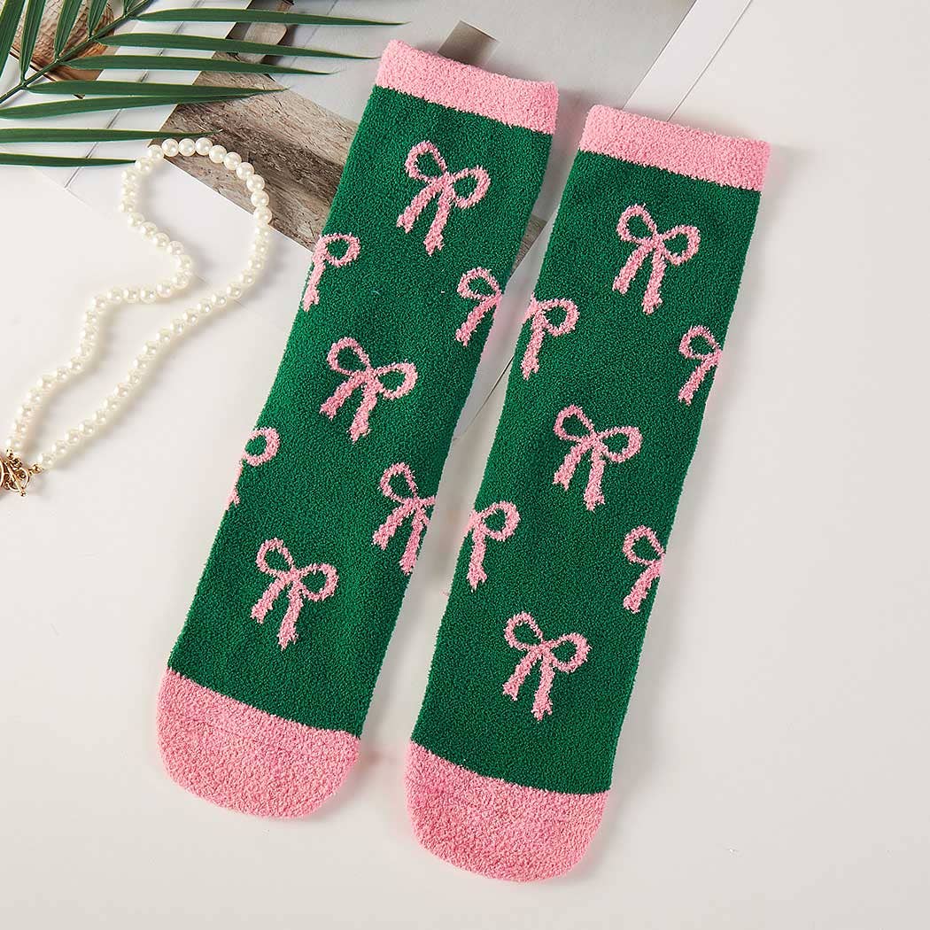 Green socks with pink bows and cuffs on a light surface.