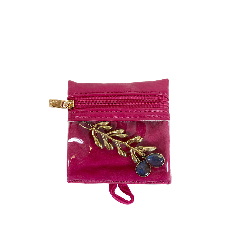 Pink jewelry pouch with a gold leaf and blue stone brooch on a white background
