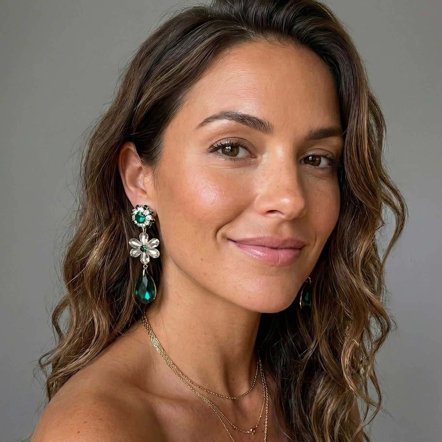 Woman wearing earrings and a necklace against a gray background