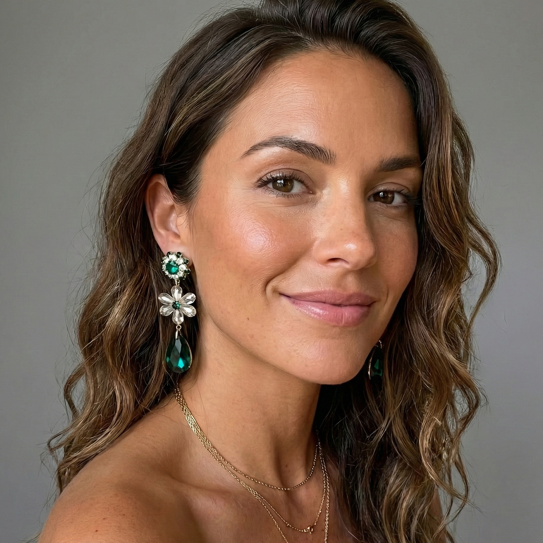 Woman wearing earrings and a necklace against a gray background