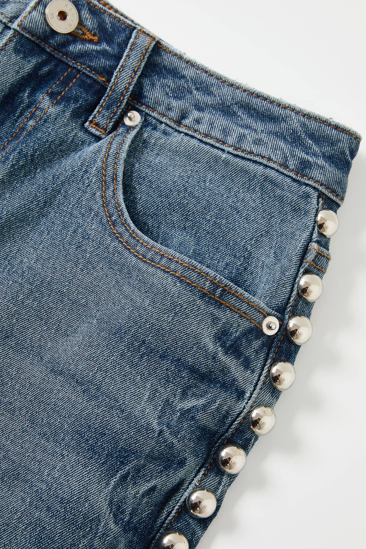 Close-up of blue jeans with silver studs on a white background