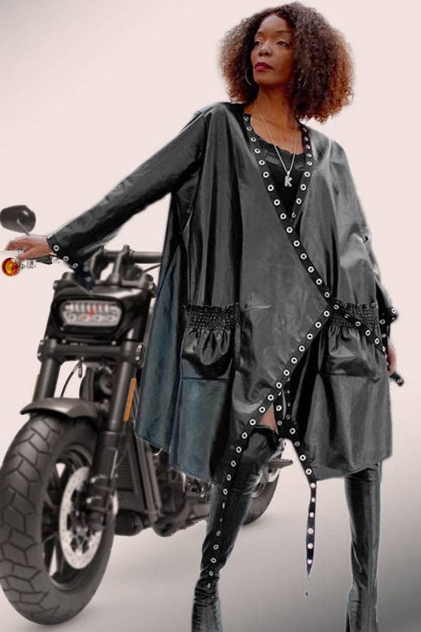 Woman in a stylish outfit standing next to a motorcycle on a plain background
