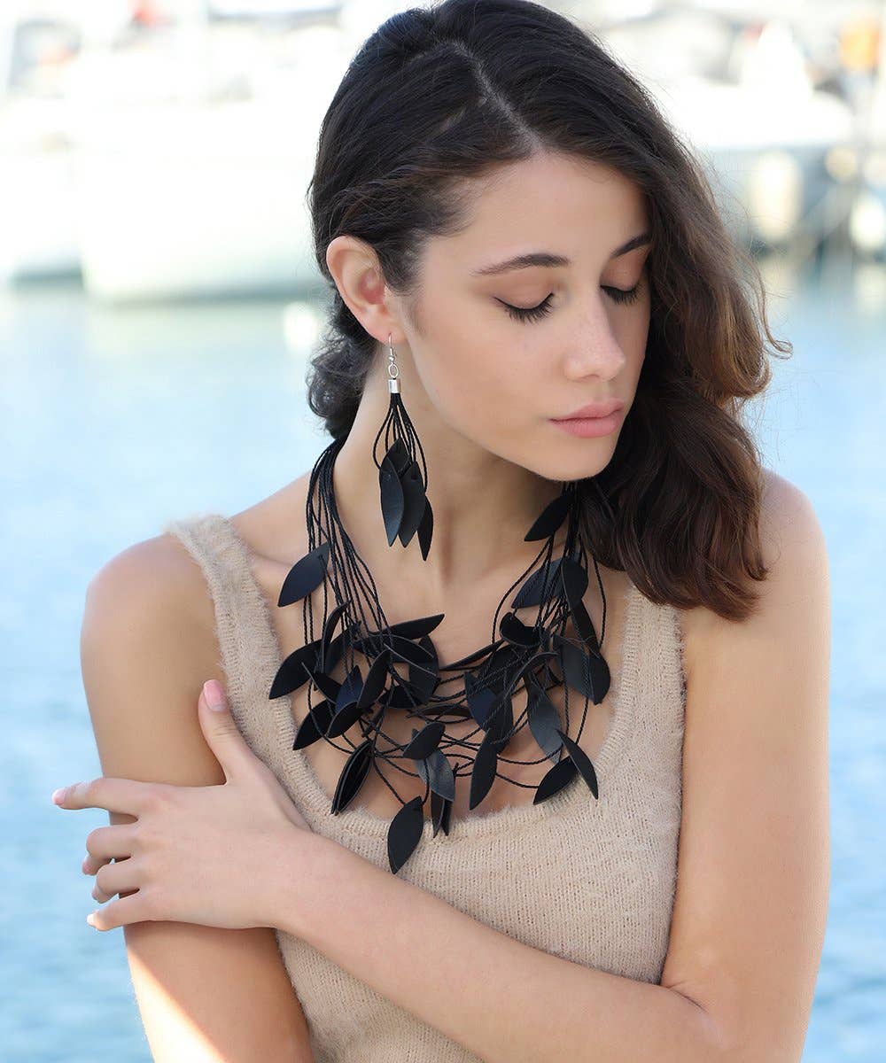 Woman wearing a black leaf-like necklace with a blurred background