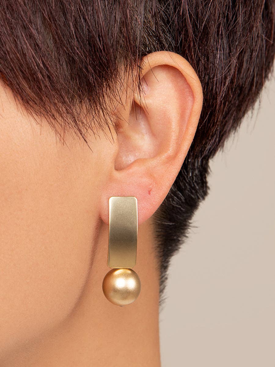 Gold earring worn by a person with a neutral background