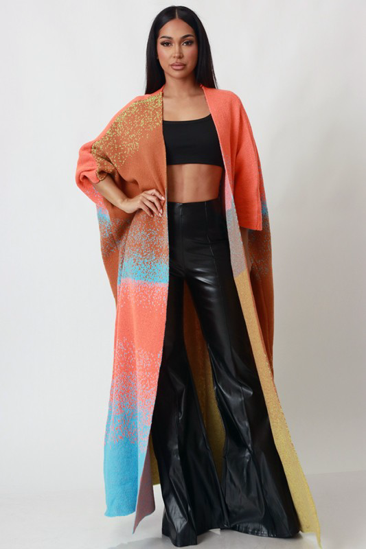 Woman wearing a long, colorful coat over a black outfit on a white background