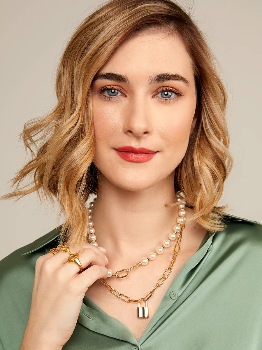 Woman wearing a gold necklace with a beige background