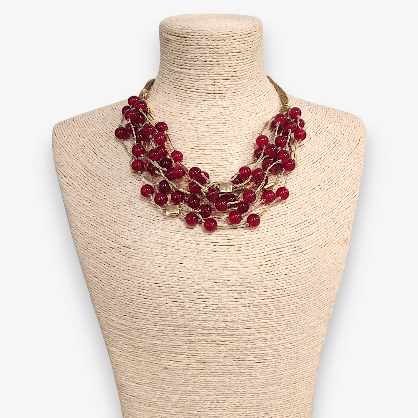 Red beaded necklace on a mannequin bust with a plain background