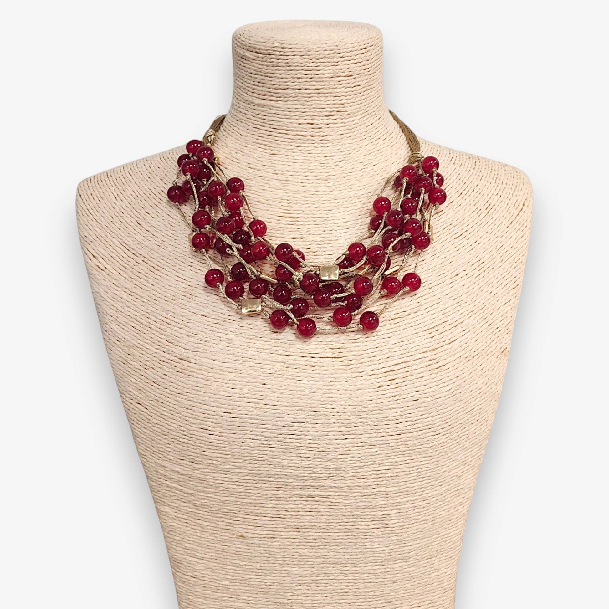 Red beaded necklace on a mannequin bust with a plain background