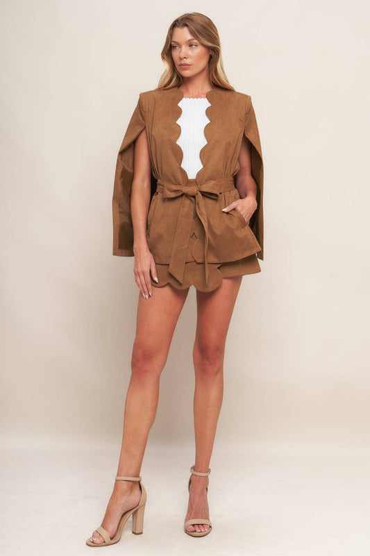 Woman wearing a brown outfit with a cape on a white background