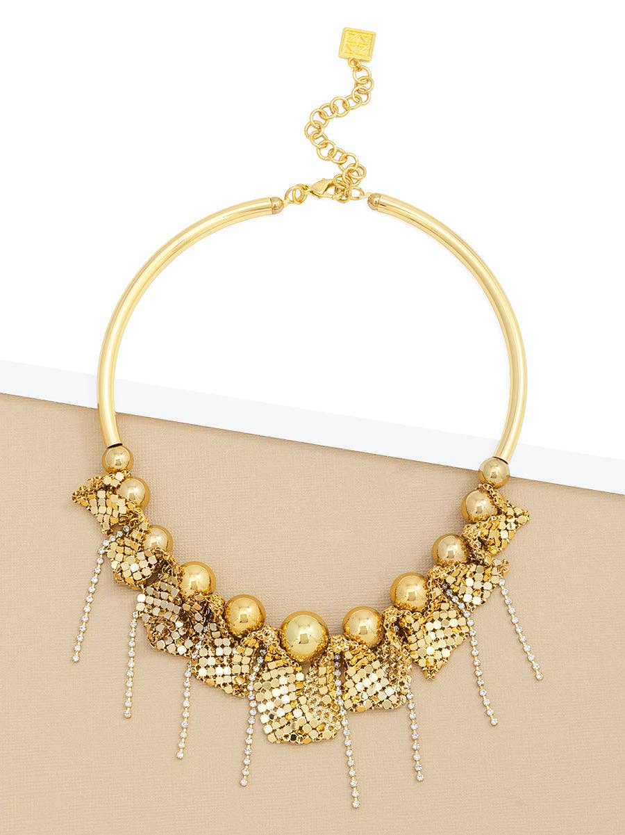 Gold necklace with beads and chain on a beige surface