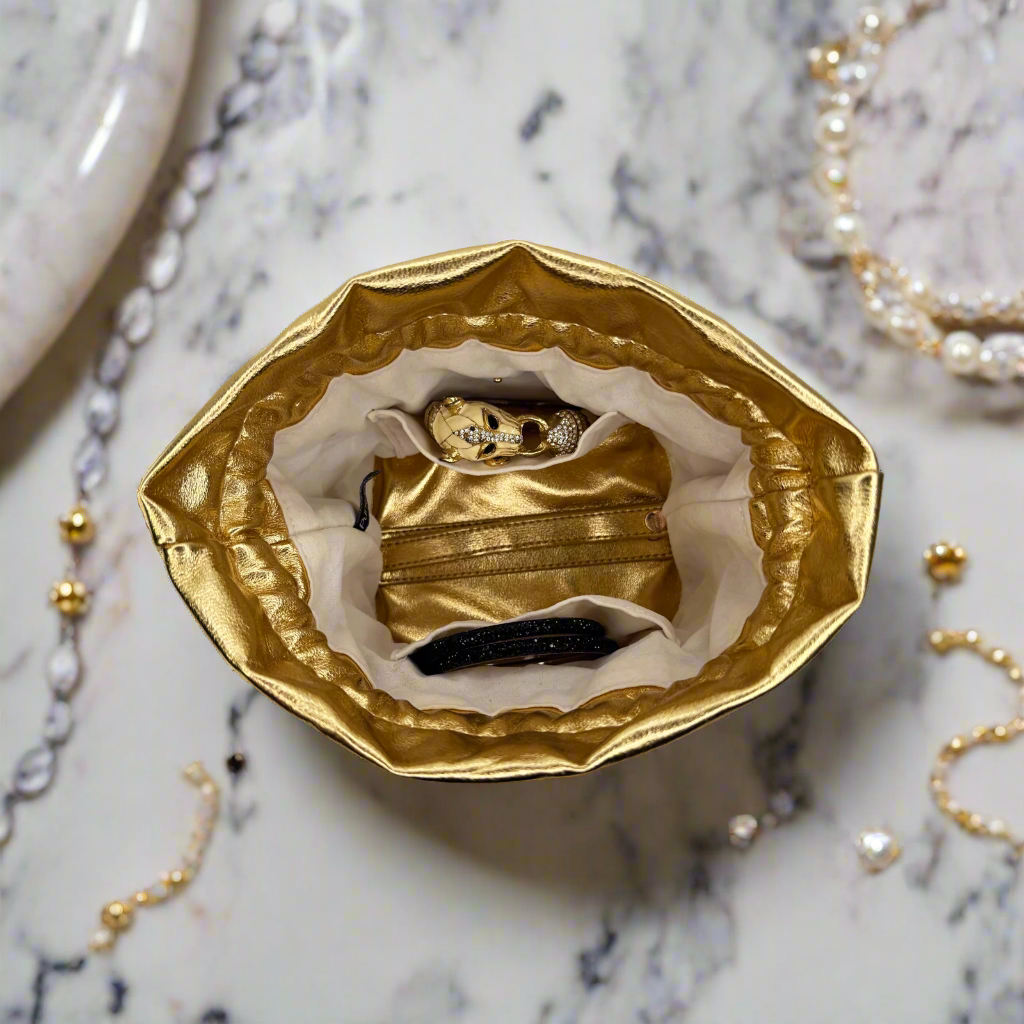 Gold jewelry box with a face mask inside on a marble surface