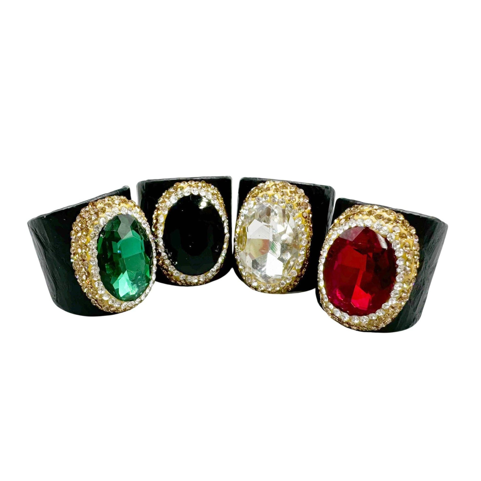 Set of four gemstone-encrusted rings on a white background