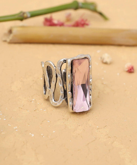 Silver ring with a pink gemstone on a beige surface
