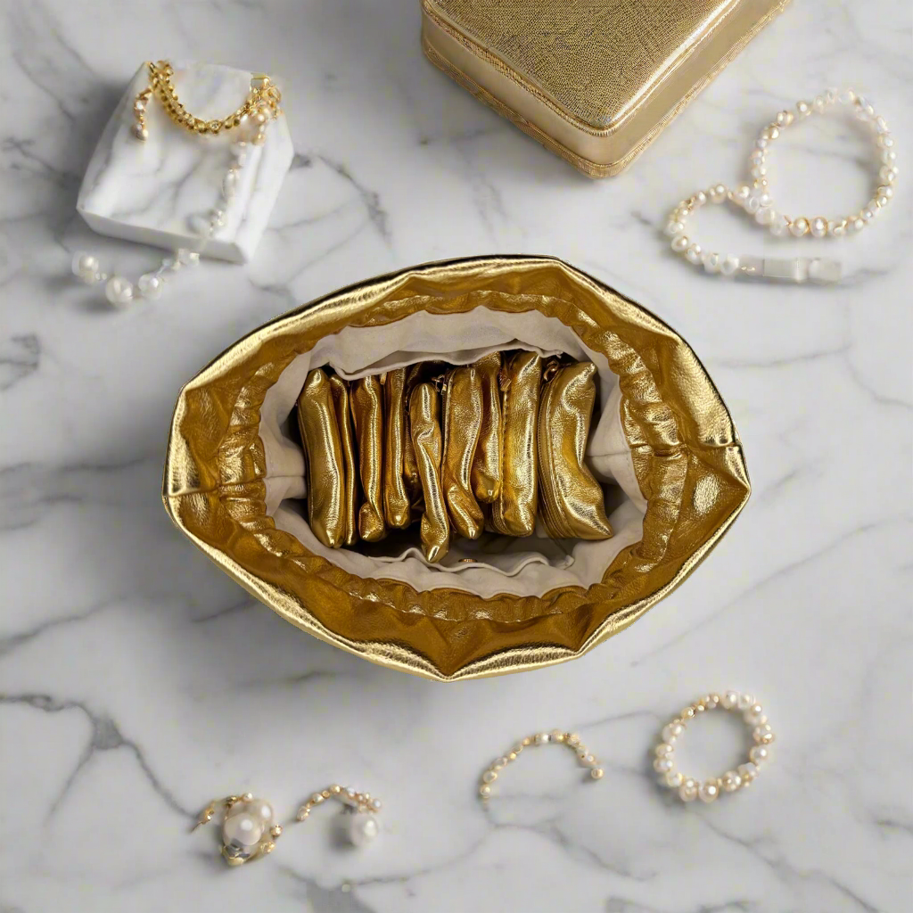 Gold jewelry dish on a marble surface with jewelry items around