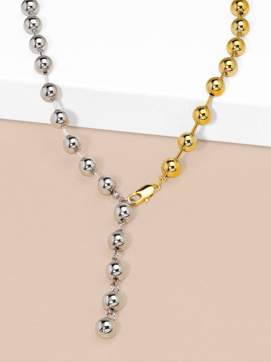 Two necklaces with silver and gold beads on a beige surface