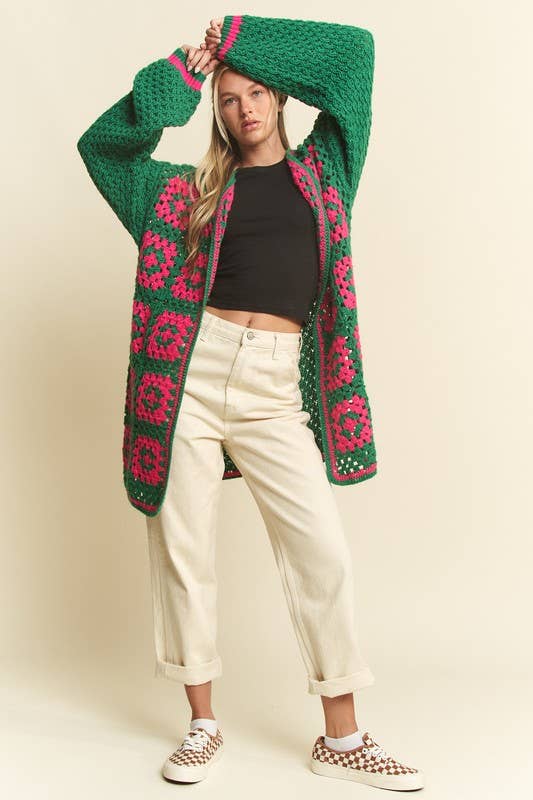 Person wearing a green and pink patterned cardigan on a beige background