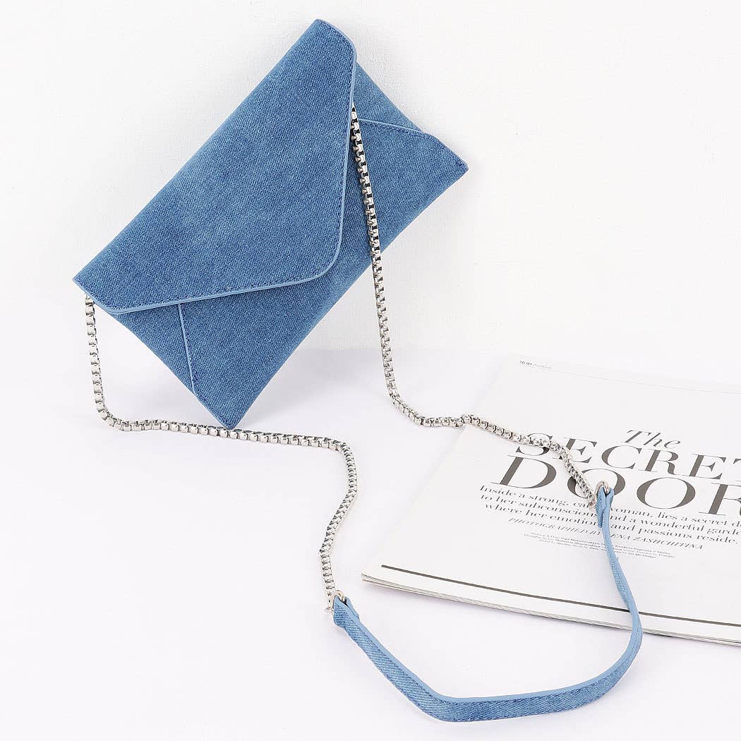 Blue denim clutch with a matching chain on a white surface