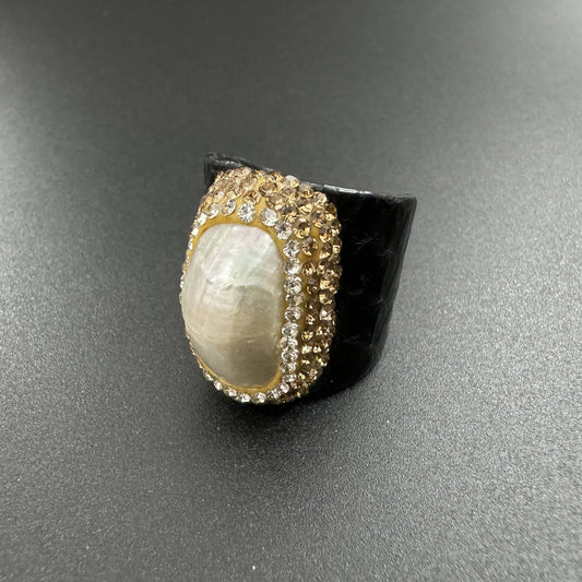 Ring with a large central stone and gold accents on a gray background