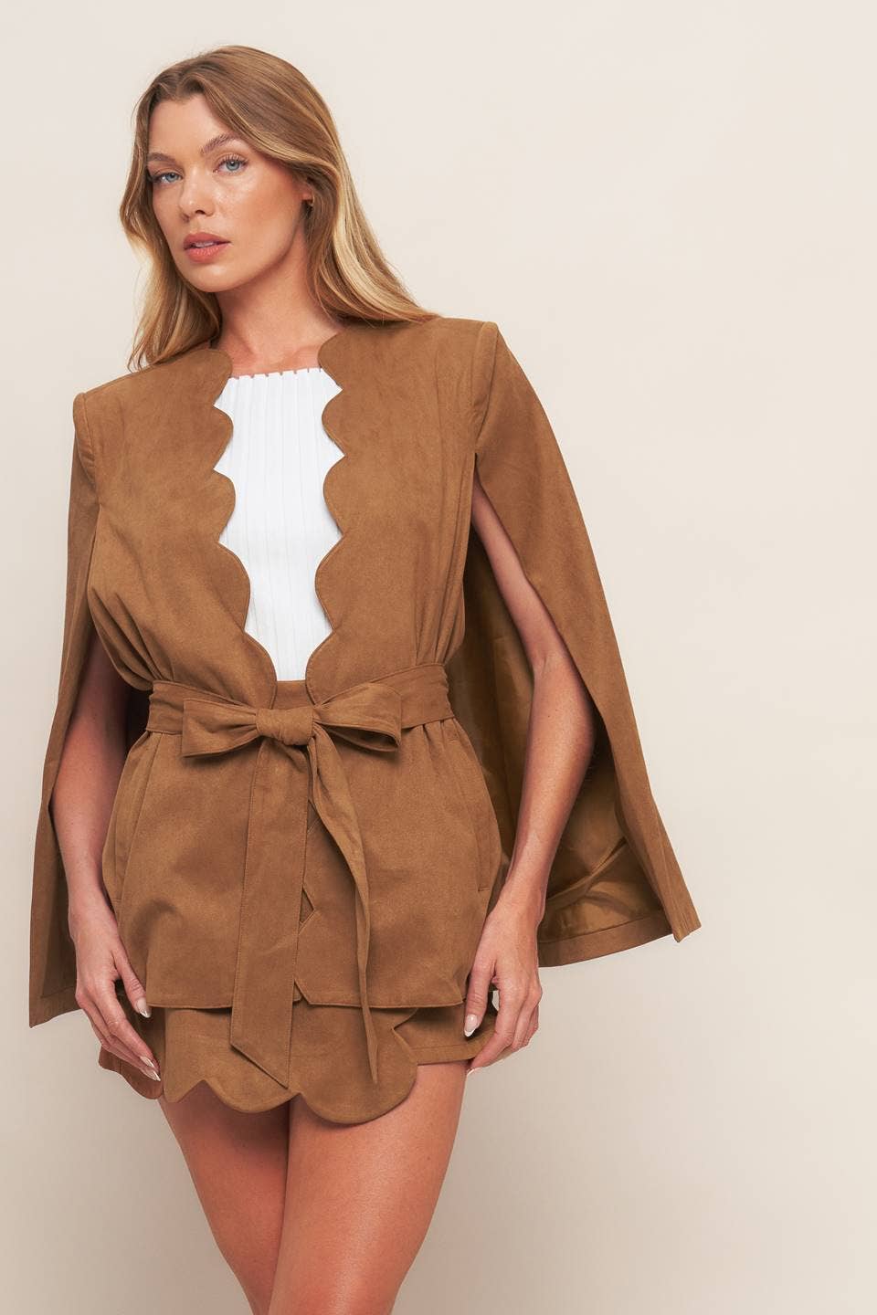 Woman wearing a brown cape dress against a plain background