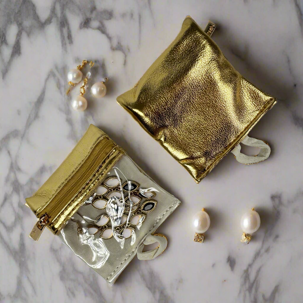 Gold jewelry pouches with jewelry on a marble surface