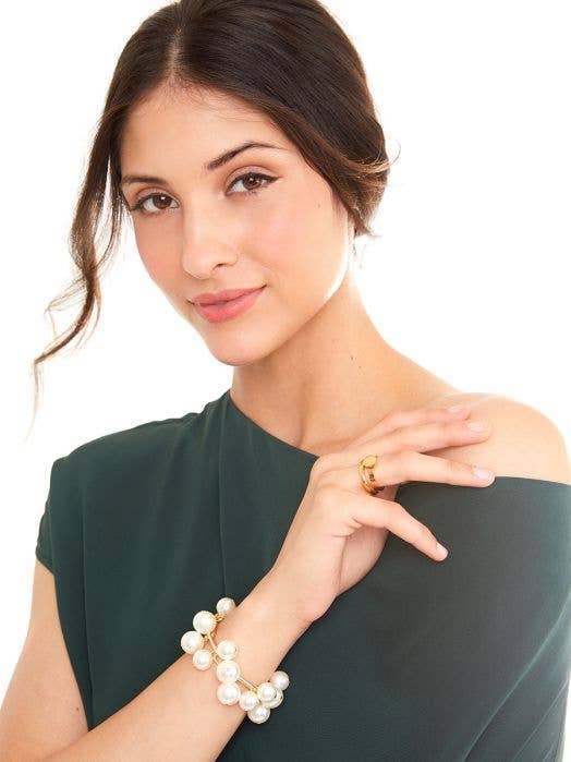 Woman wearing a pearl bracelet and gold ring on a white background